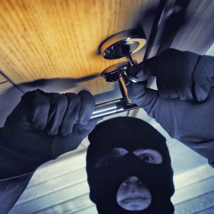 Burglar picking the lock on a wooden door