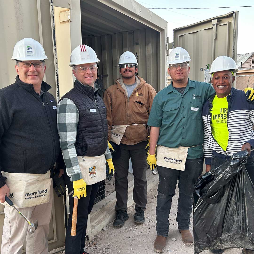 Five members of the First Impression Ironworks team. posing for a picture together, outside of a storage container.