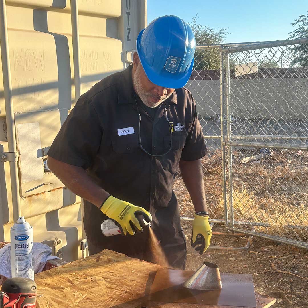 First Impression Ironworks employee spray painting wood