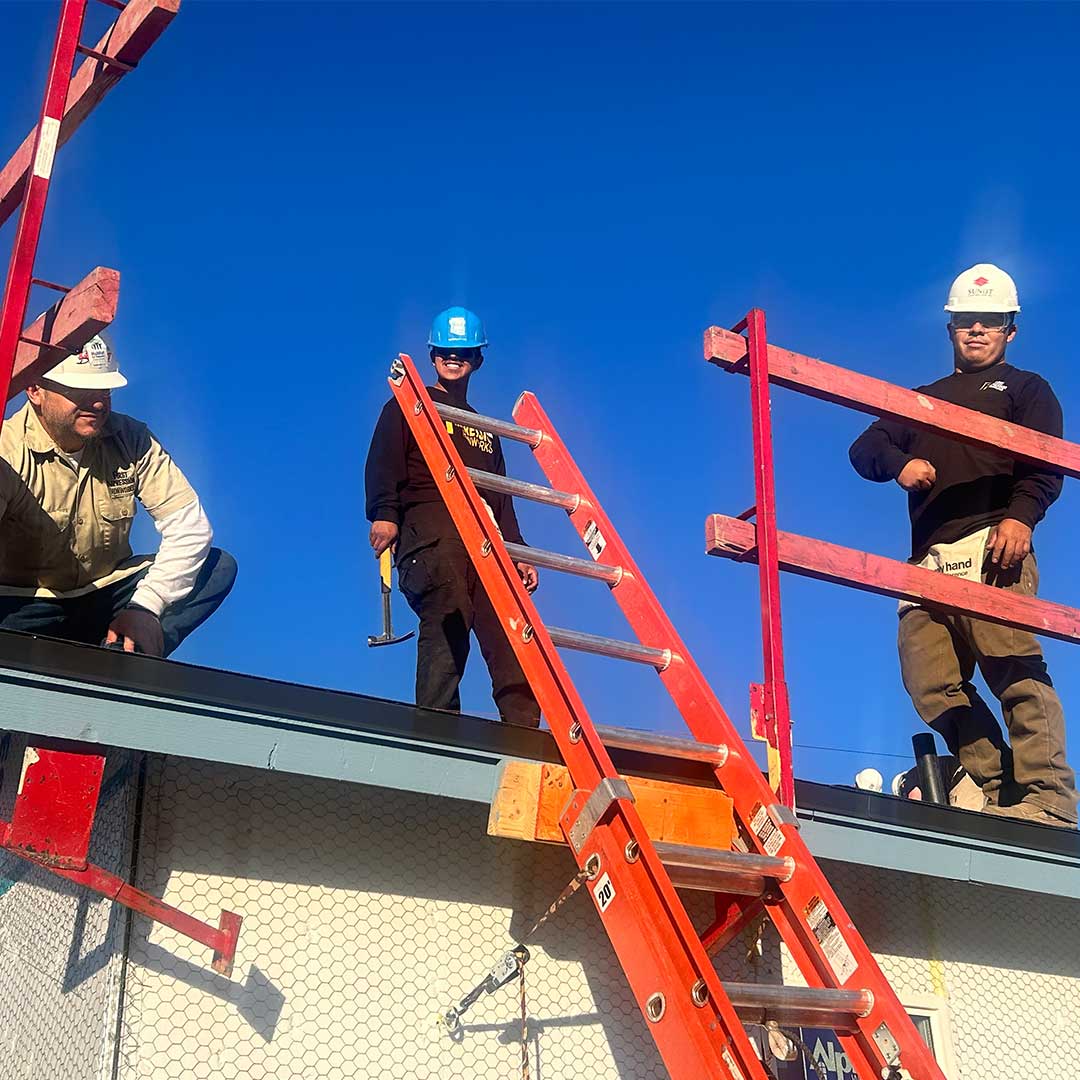 Three First Impression Ironworks employees standing on the roof of a home being built