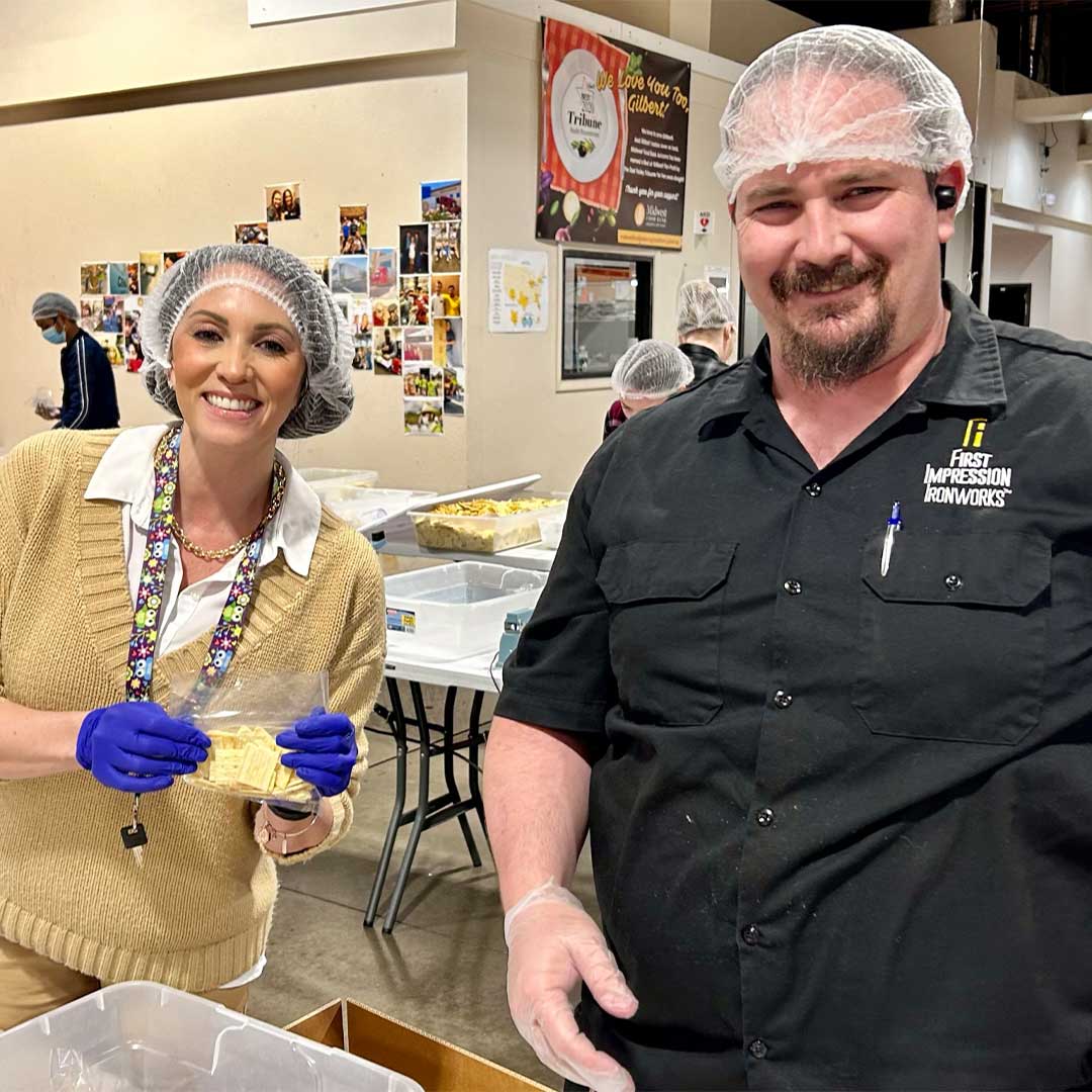 Two First Impression Ironworks team members packing baggies of food