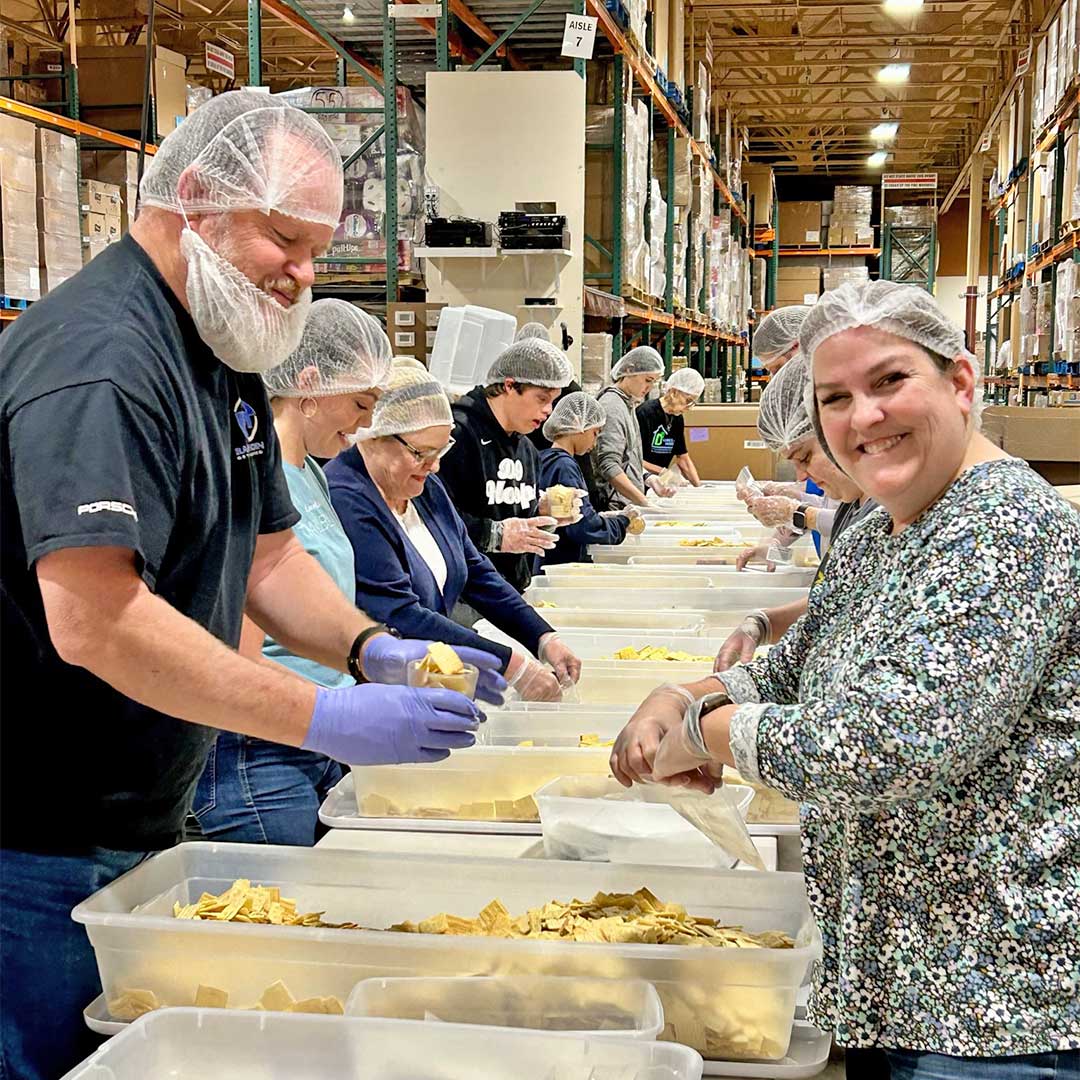 FII team members working at tables, bagging up food, to support First Impression Ironworks