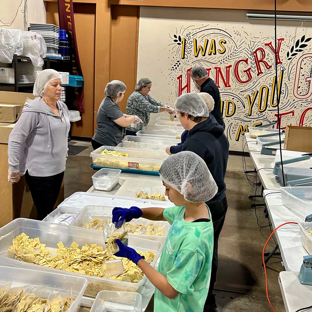 Line of First Impression Ironworks employees and family members volunteering their time at Midwest Food Bank